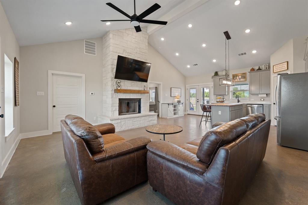 1031 Augustus Court Rio Vista, TX 76093 - Photo 4 of 30 Spacious living area featuring a vaulted ceiling and a stone-clad fireplace with a natural wood mantel