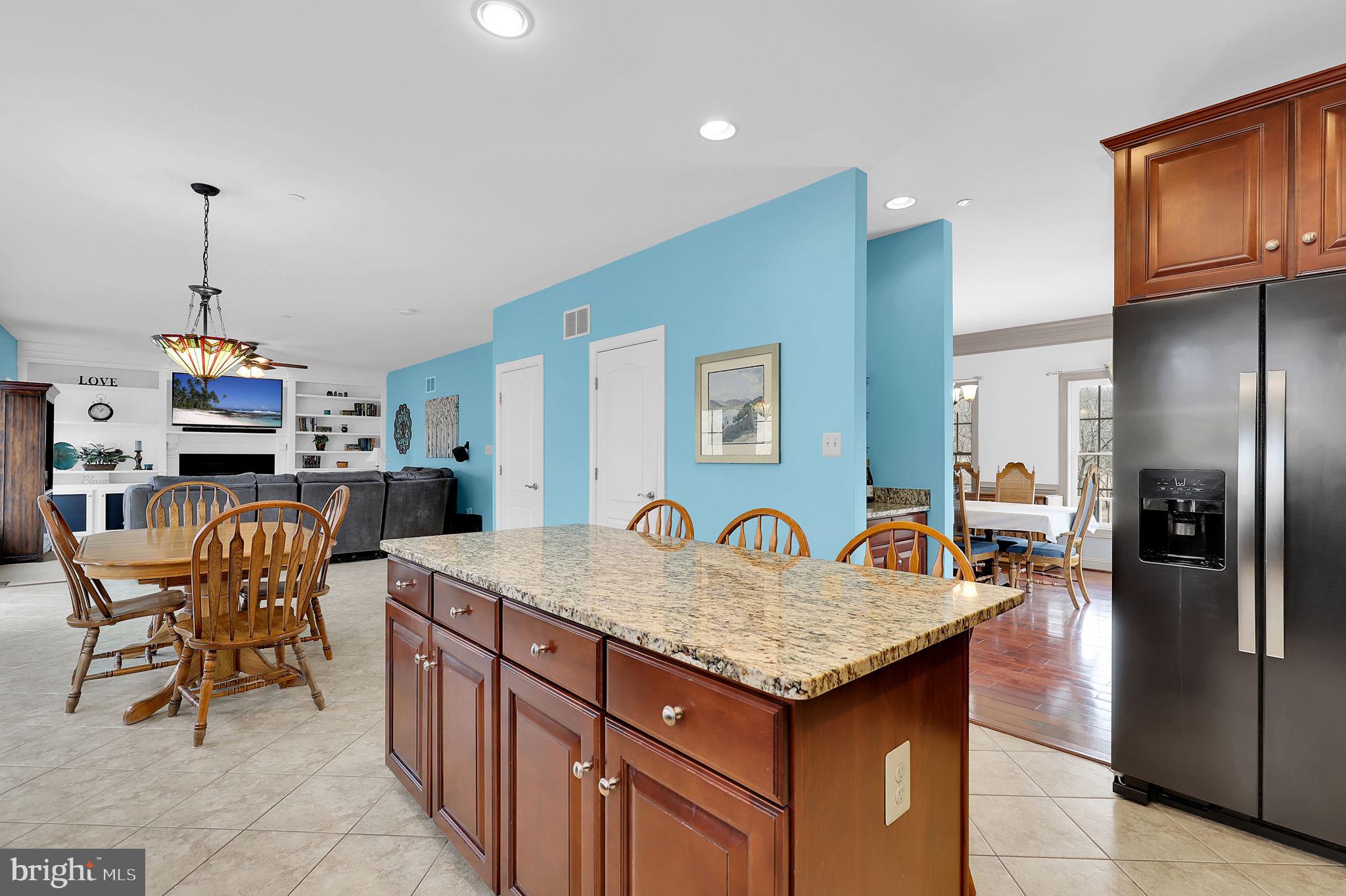 6024 Old Bohn Road Mount Airy, MD 21771 - Photo 19 of 46 a open kitchen with granite countertop a refrigerator a stove and a dining table with wooden floor