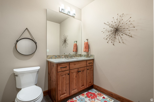 2331 West Entrada Trail, Unit 61 St. George, UT 84770 - Photo 45 of 69 Bathroom vanity featuring a light-colored countertop with an undermount sink, a tiled backsplash, and a wood-finish cabinet with dark hardware