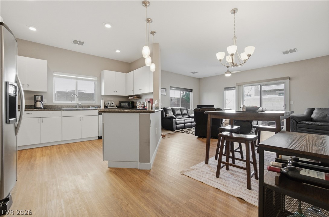 6316 Snap Ridge Street, Unit 101 North Las Vegas, NV 89081 - Photo 2 of 41 Enjoy a seamless transition between the living room, dining area, and kitchen, enhanced by neutral tones and cohesive flooring throughout.
