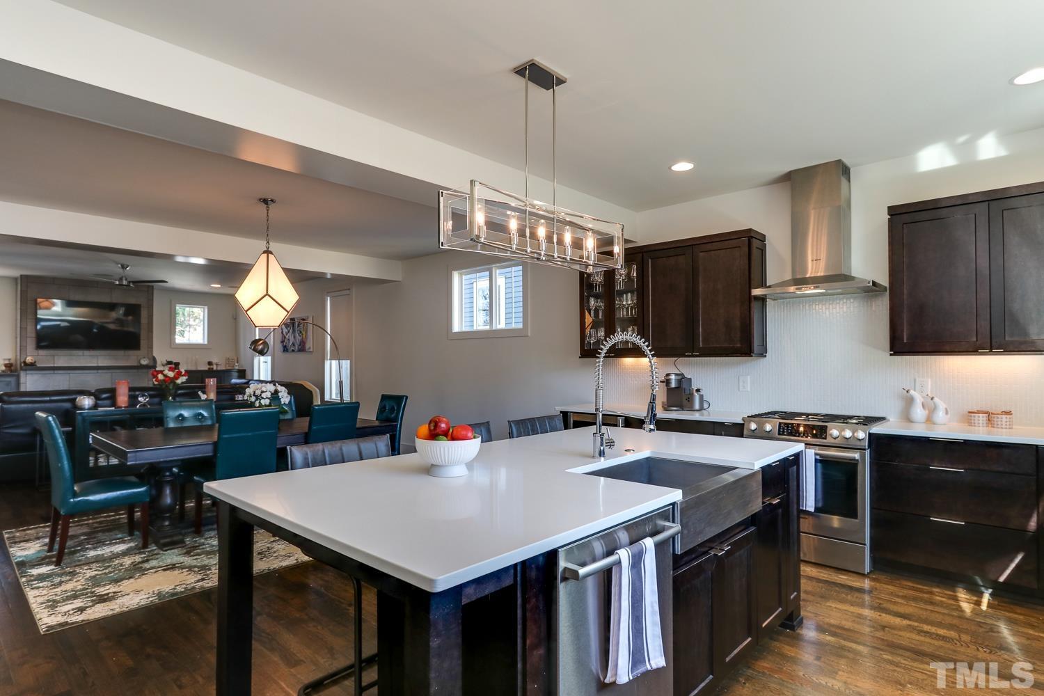 107 Revival Way Raleigh, NC 27608 - Photo 9 of 31 a kitchen with a stove a sink dishwasher a dining table and chairs with wooden floor