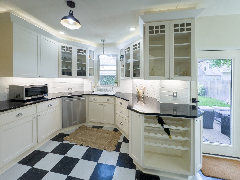 1512 Northwood Road Austin, TX 78703 - Photo 17 of 24 Kitchen featuring light flooring, backsplash, pendant lighting, appliances with stainless steel finishes, and white cabinetry