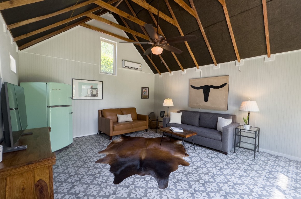 1512 Northwood Road Austin, TX 78703 - Photo 21 of 24 Living area with high vaulted ceiling, a ceiling fan, wood walls, and a wall unit AC