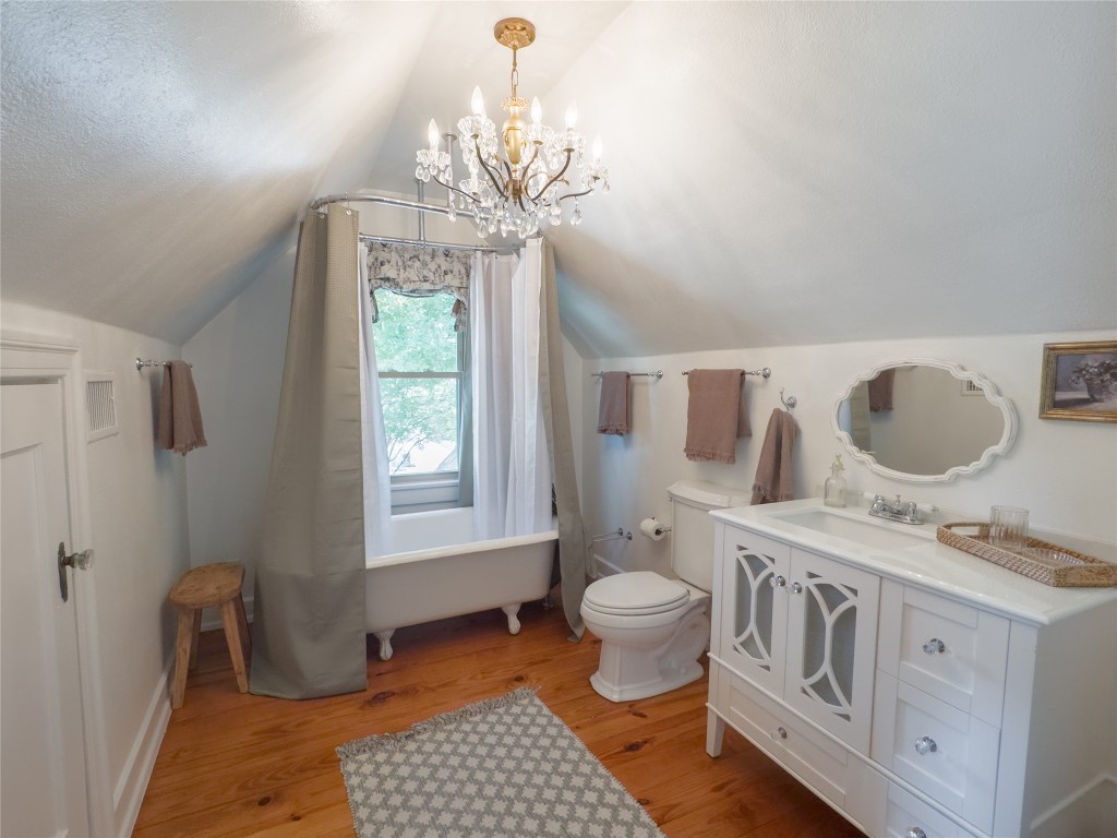 1512 Northwood Road Austin, TX 78703 - Photo 6 of 24 Full bathroom with vanity, a chandelier, light wood-style floors, a freestanding tub, and vaulted ceiling