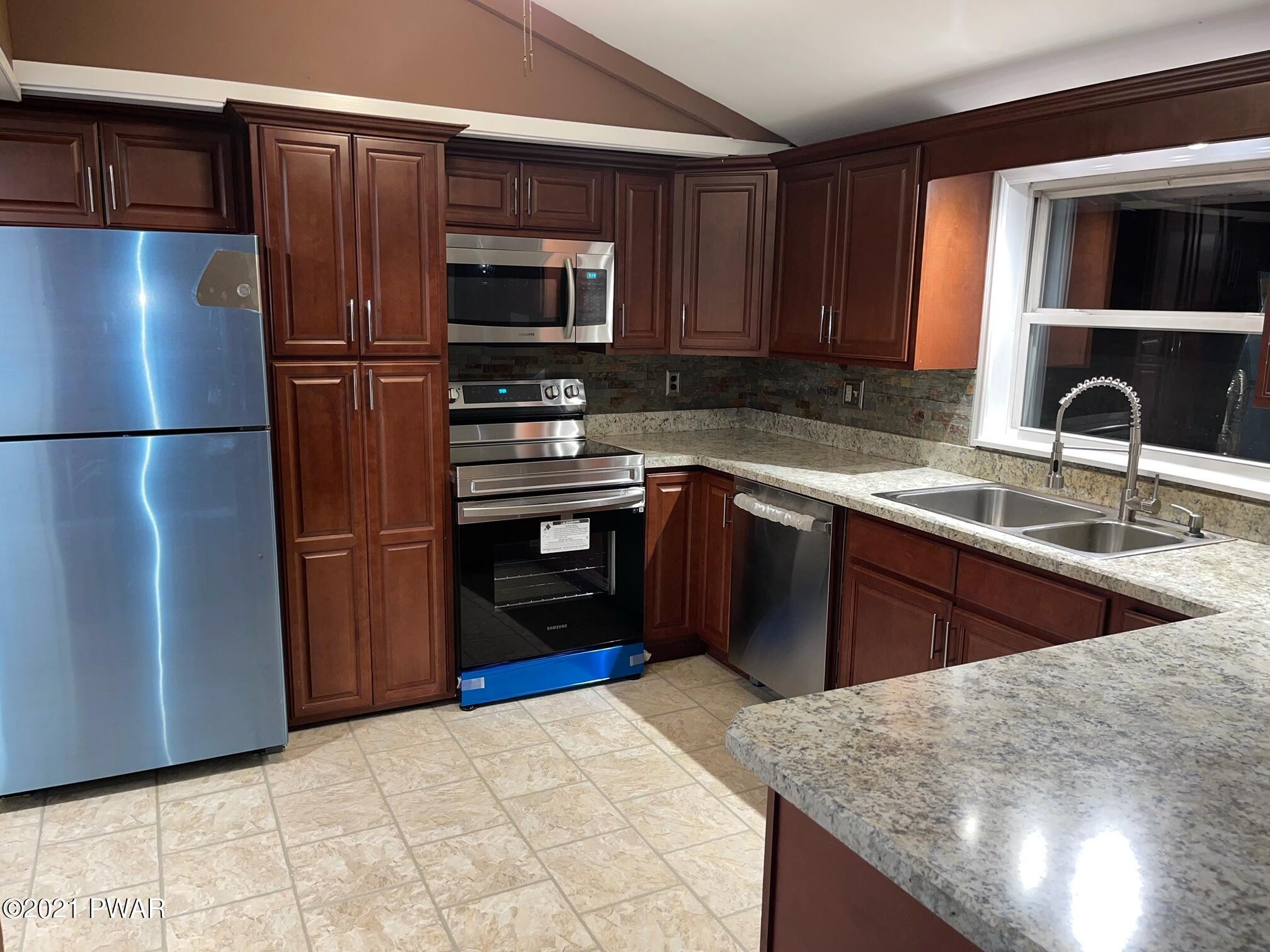110 Red Pine Road Dingmans Ferry, PA 18328 - Photo 2 of 13 a kitchen with stainless steel appliances granite countertop a refrigerator a stove a sink and a microwave