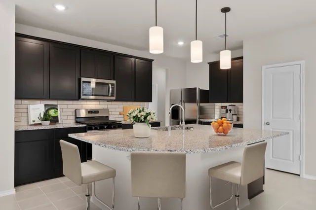 a kitchen with stainless steel appliances kitchen island granite countertop a refrigerator a stove a sink a dining table and chairs with wooden floor
