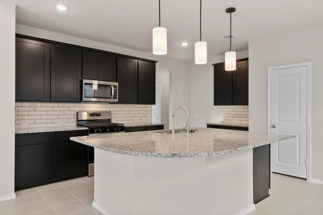 a kitchen with stainless steel appliances granite countertop a sink a stove a refrigerator and island