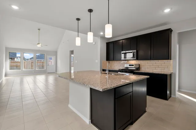 a kitchen with kitchen island granite countertop a sink stove and refrigerator