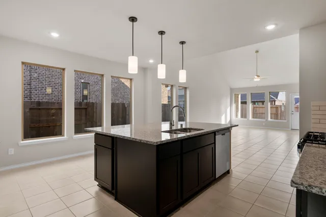 a kitchen with granite countertop a stove a sink and a counter top space
