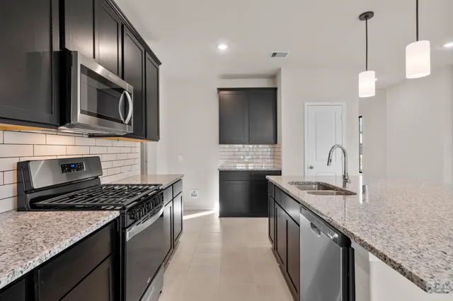 a kitchen with stainless steel appliances granite countertop a sink stove and refrigerator