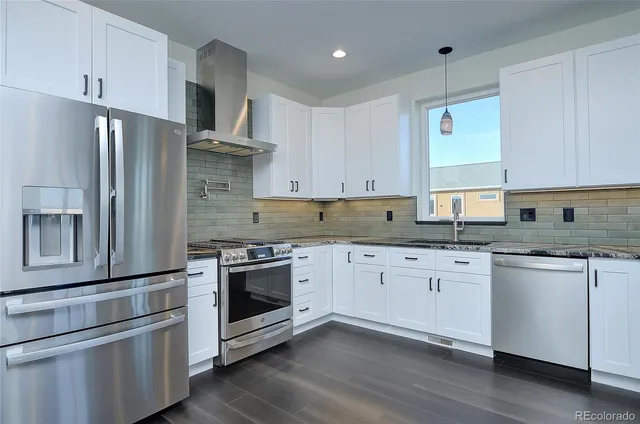 a kitchen with stainless steel appliances granite countertop a stove a refrigerator and a stove top oven