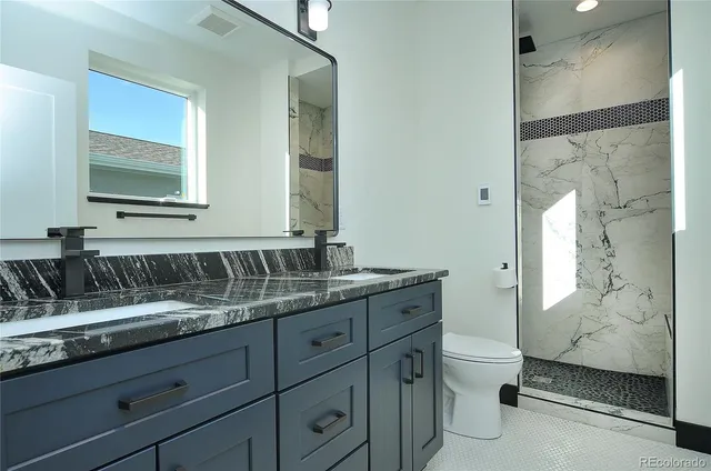 a bathroom with a granite countertop sink toilet and shower