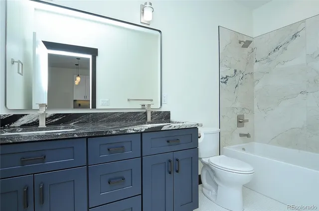 a bathroom with a granite countertop toilet a sink and a bathtub