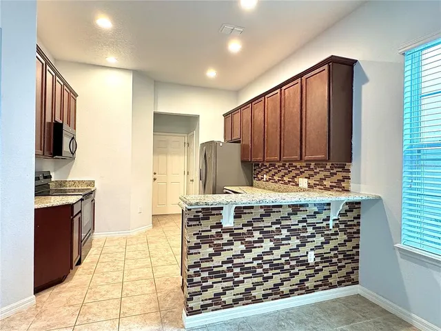 a kitchen with stainless steel appliances kitchen island granite countertop a refrigerator and a stove top oven