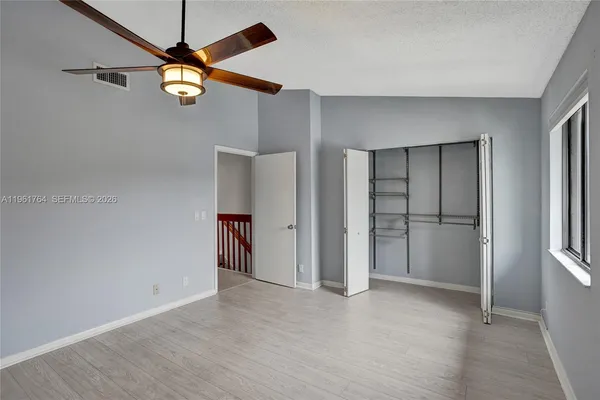 an empty room with a window and a ceiling fan