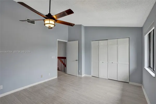 a view of an empty room and chandelier fan