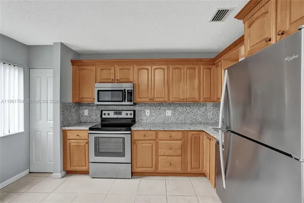 a kitchen with stainless steel appliances granite countertop a refrigerator sink and stove