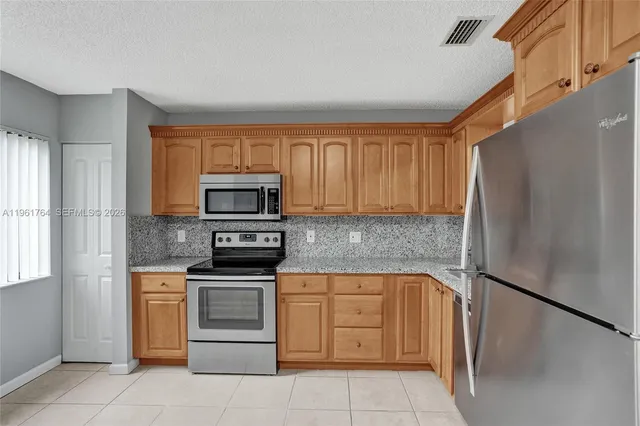 a kitchen with stainless steel appliances granite countertop a refrigerator sink and stove