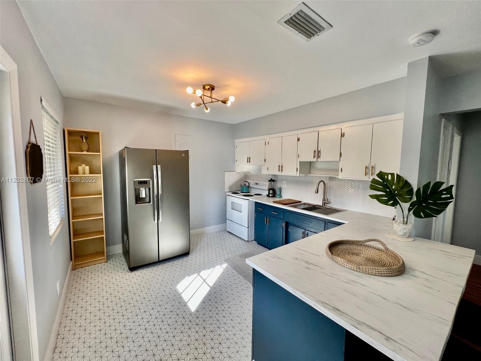 3095 Southwest 21st Street, Unit 1 Miami, FL 33145 - Photo 5 of 15 a kitchen with stainless steel appliances kitchen island granite countertop a refrigerator a sink dishwasher a stove with white cabinets and wooden floor