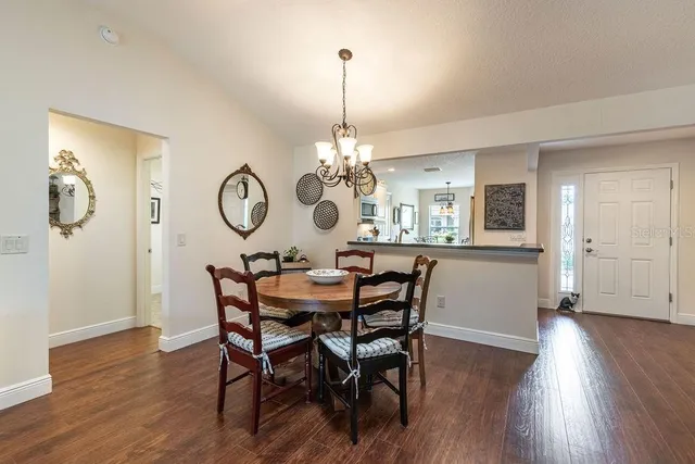 a dining room with wooden floor a chandelier a wooden table and chairs