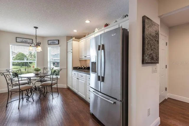 a kitchen with stainless steel appliances a refrigerator a stove a refrigerator a dining table and chairs with wooden floor