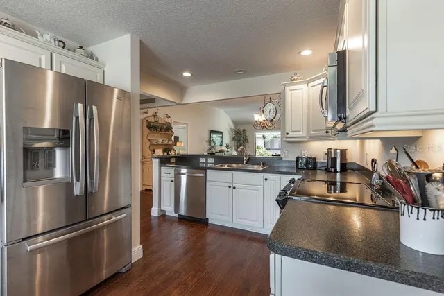a kitchen with stainless steel appliances granite countertop a refrigerator a sink a stove and white cabinets