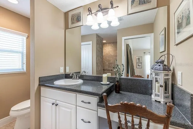 a bathroom with a granite countertop sink a toilet and a mirror