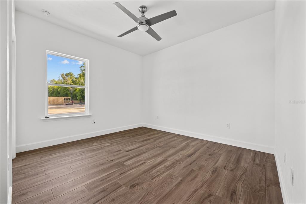 1086 Southwest 67th Drive Gainesville, FL 32607 - Photo 28 of 37 an empty room with wooden floor ceiling fan and windows