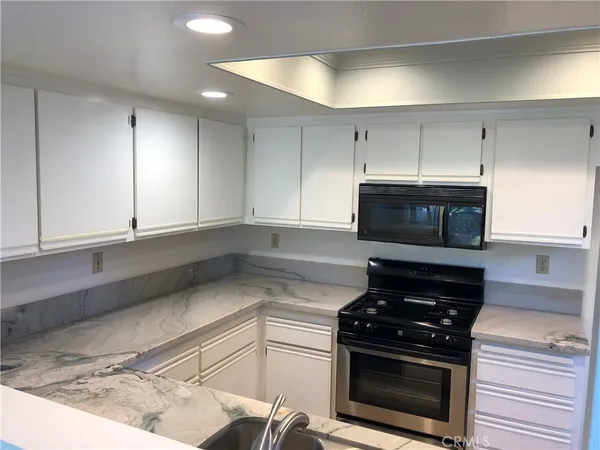 a kitchen with granite countertop a stove and a microwave