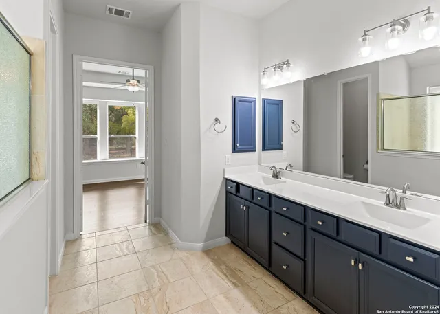 a spacious bathroom with a double vanity sink a mirror and a shower