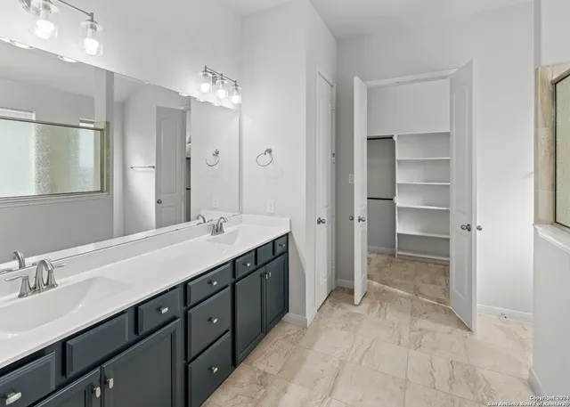 a spacious bathroom with a double vanity sink a large mirror and a shower