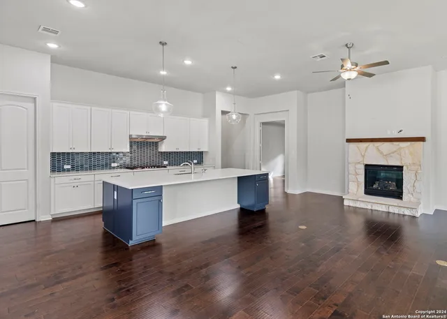 a large kitchen with a center island wooden floor stainless steel appliances and cabinets