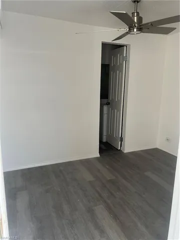 an empty room with wooden floor closet and windows