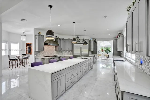 a kitchen with stainless steel appliances kitchen island granite countertop a table and chairs in it