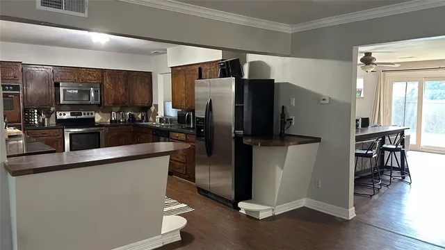 a kitchen with stainless steel appliances a refrigerator a stove a sink a dining table and chairs