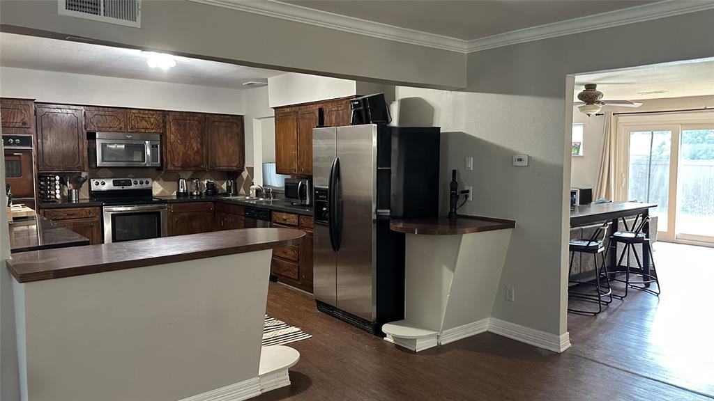 13533 Emeline Street Farmers Branch, TX 75234 - Photo 8 of 29 a kitchen with stainless steel appliances a refrigerator a stove a sink a dining table and chairs