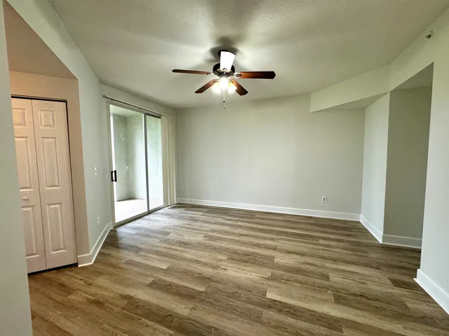 an empty room with wooden floor fan and windows