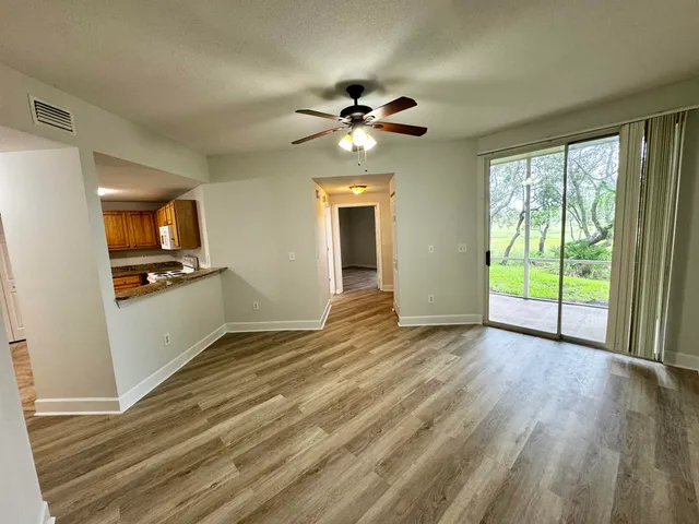 a view of an empty room with window and wooden floor