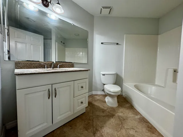 a bathroom with a granite countertop toilet a sink and a bathtub