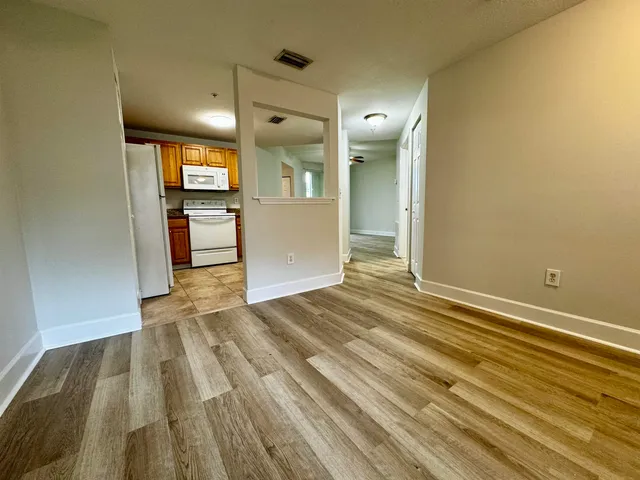 a view of a room with wooden floor and a kitchen