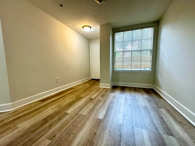 an empty room with wooden floor and windows