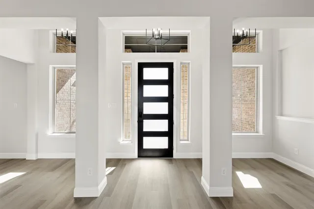 an empty room with wooden floor cabinet and windows