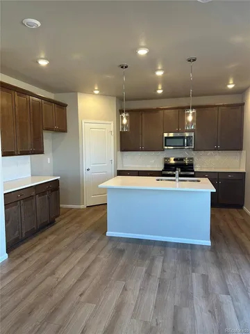 a large kitchen with kitchen island a sink dishwasher a stove and a refrigerator with wooden floor