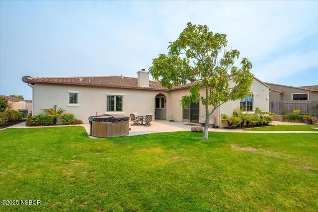 a view of a patio with table and chairs under an umbrella with large trees