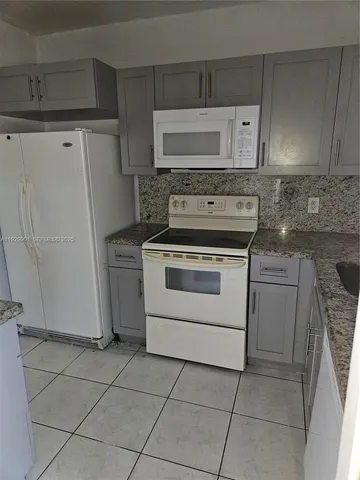 a white kitchen with granite countertop white cabinets and white appliances