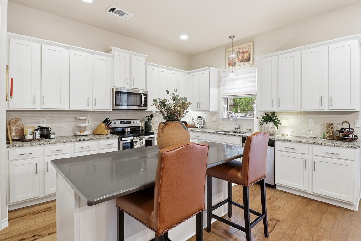 103 Kings Way Horseshoe Bay, TX 78657 - Photo 4 of 20 a kitchen with stainless steel appliances granite countertop a stove top oven a refrigerator a sink and a dining table with white cabinets