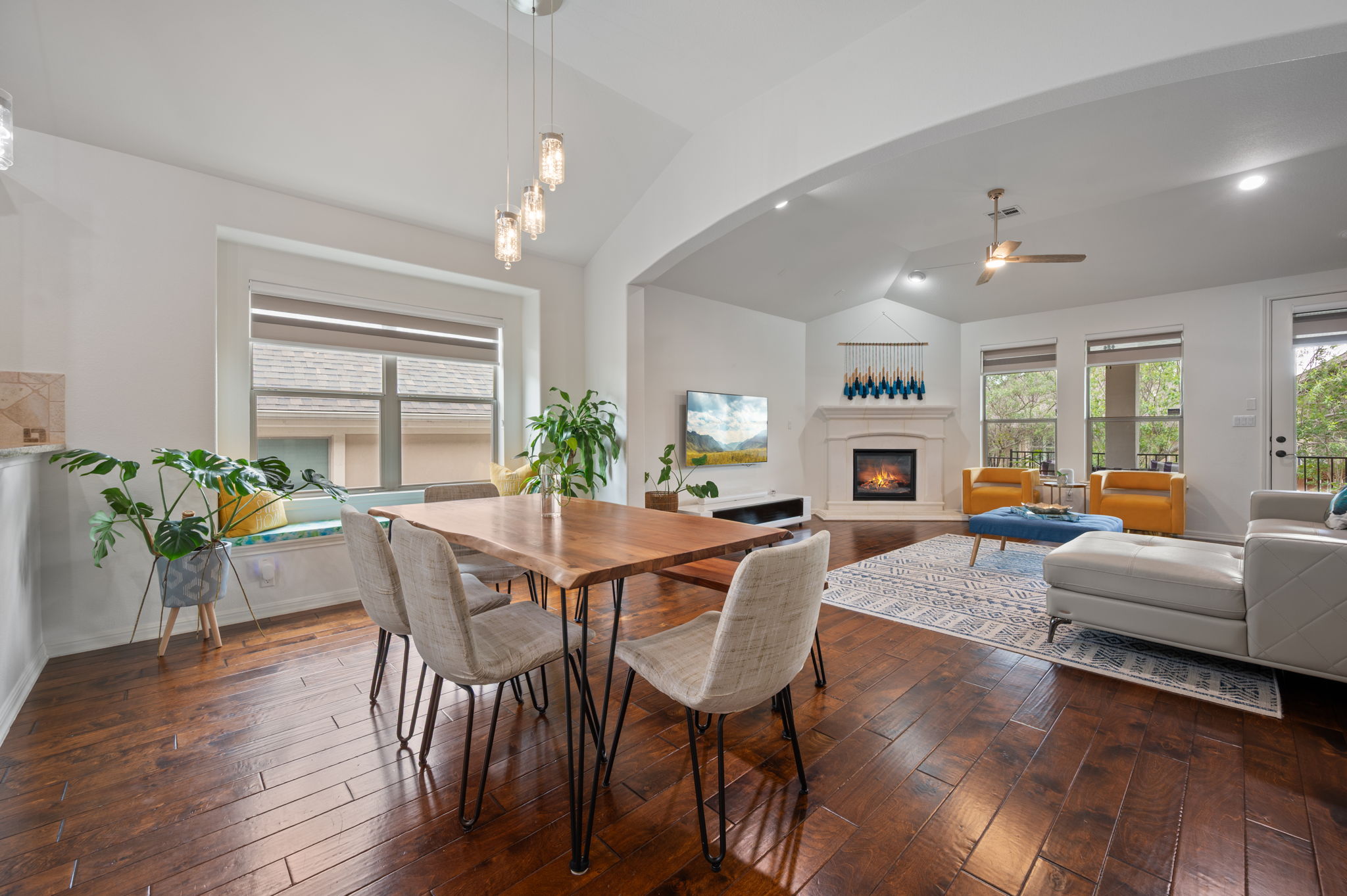 4220 Tambre Bend Austin, TX 78738 - Photo 11 of 28 Dining room featuring ceiling fan, lofted ceiling, dark wood-type flooring, a glass covered fireplace, and healthy amount of natural light