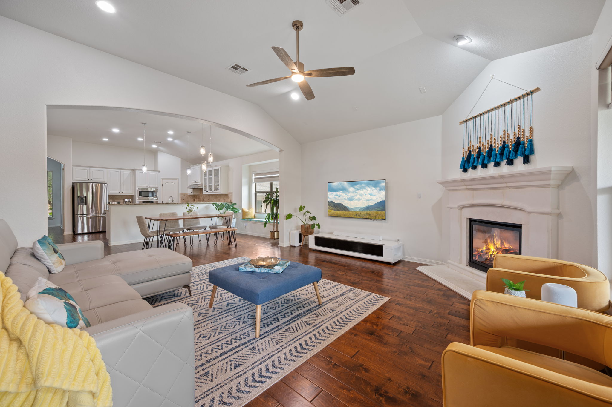 4220 Tambre Bend Austin, TX 78738 - Photo 13 of 28 Living area featuring dark wood finished floors, ceiling fan, vaulted ceiling, a glass covered fireplace, and arched walkways