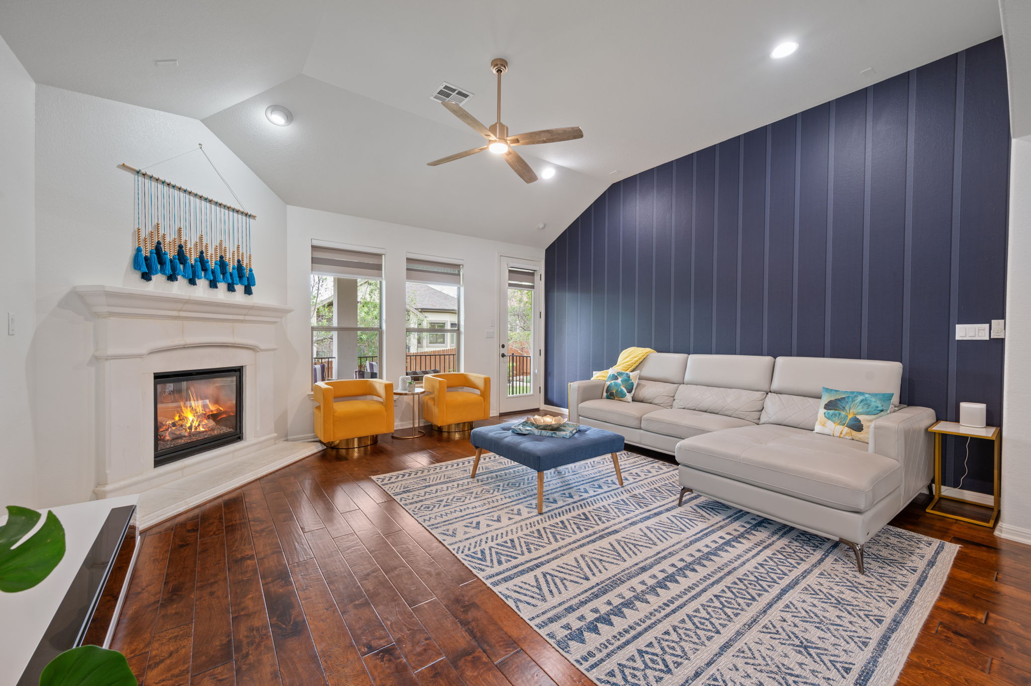 4220 Tambre Bend Austin, TX 78738 - Photo 14 of 28 Living room featuring an accent wall, ceiling fan, a glass covered fireplace, lofted ceiling, and dark wood-style flooring
