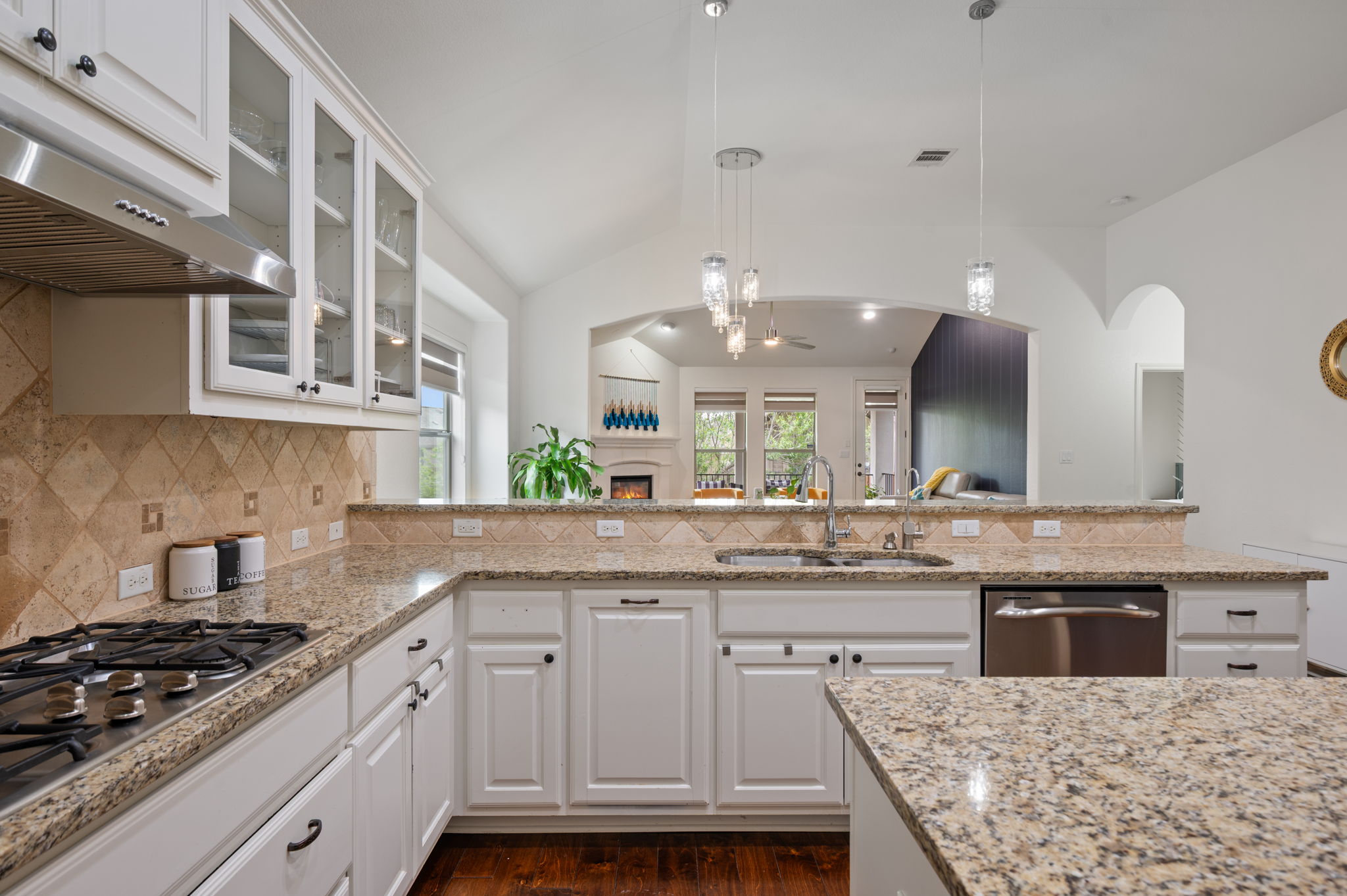 4220 Tambre Bend Austin, TX 78738 - Photo 9 of 28 Kitchen featuring white cabinetry, glass fronted cabinets, light stone counters, decorative light fixtures, and vaulted ceiling